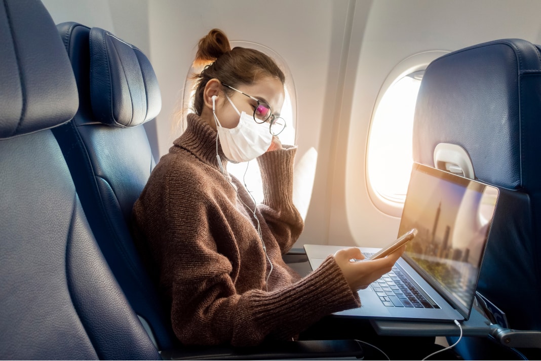 Woman wearing a mask while travelling on an airplane