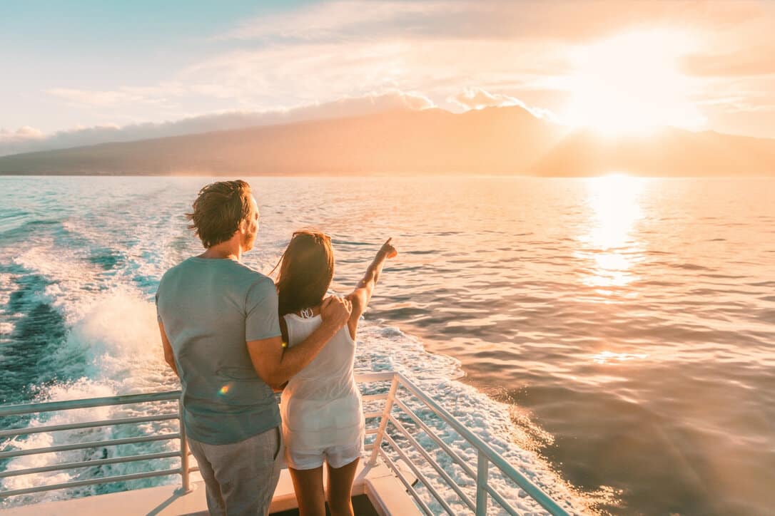 A couple watching the sunset on board while following the covid safety protocols for cruises.