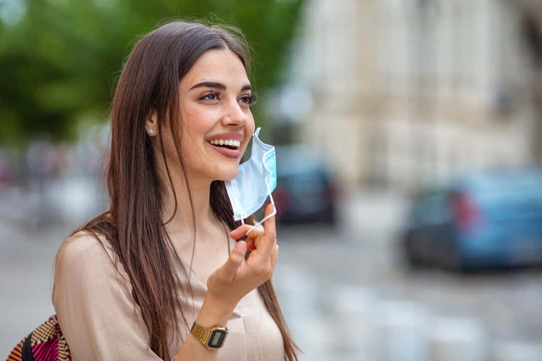 Young woman smiling while taking her covid mask off.