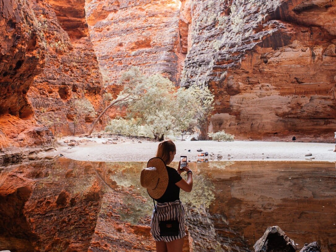 Young woman creating content for her travel TikTok account in a canyon.