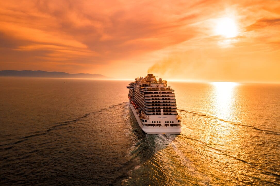 Cruise ship navegating in the ocean at sunset.