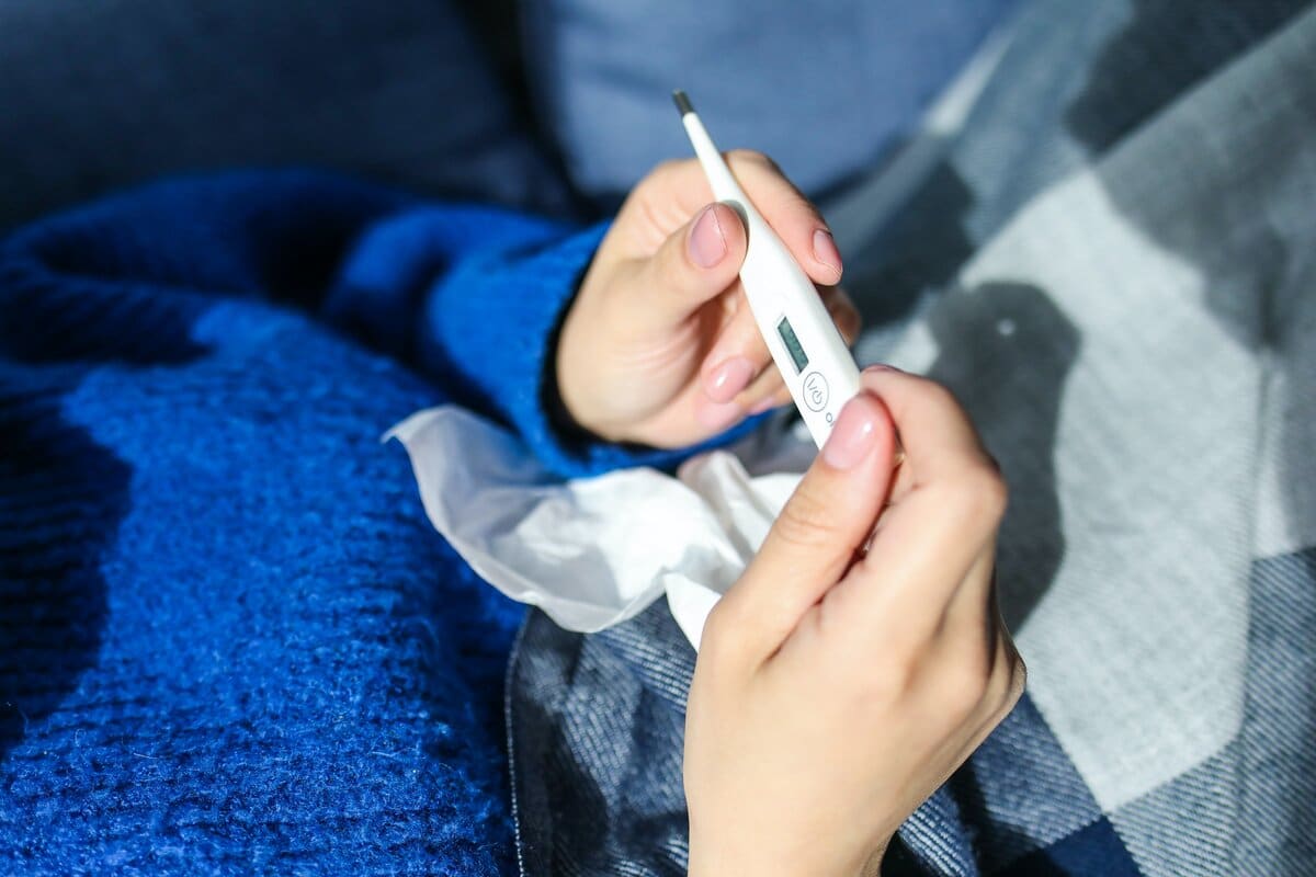 Person looking at a thermometer checkig whether they have fever.