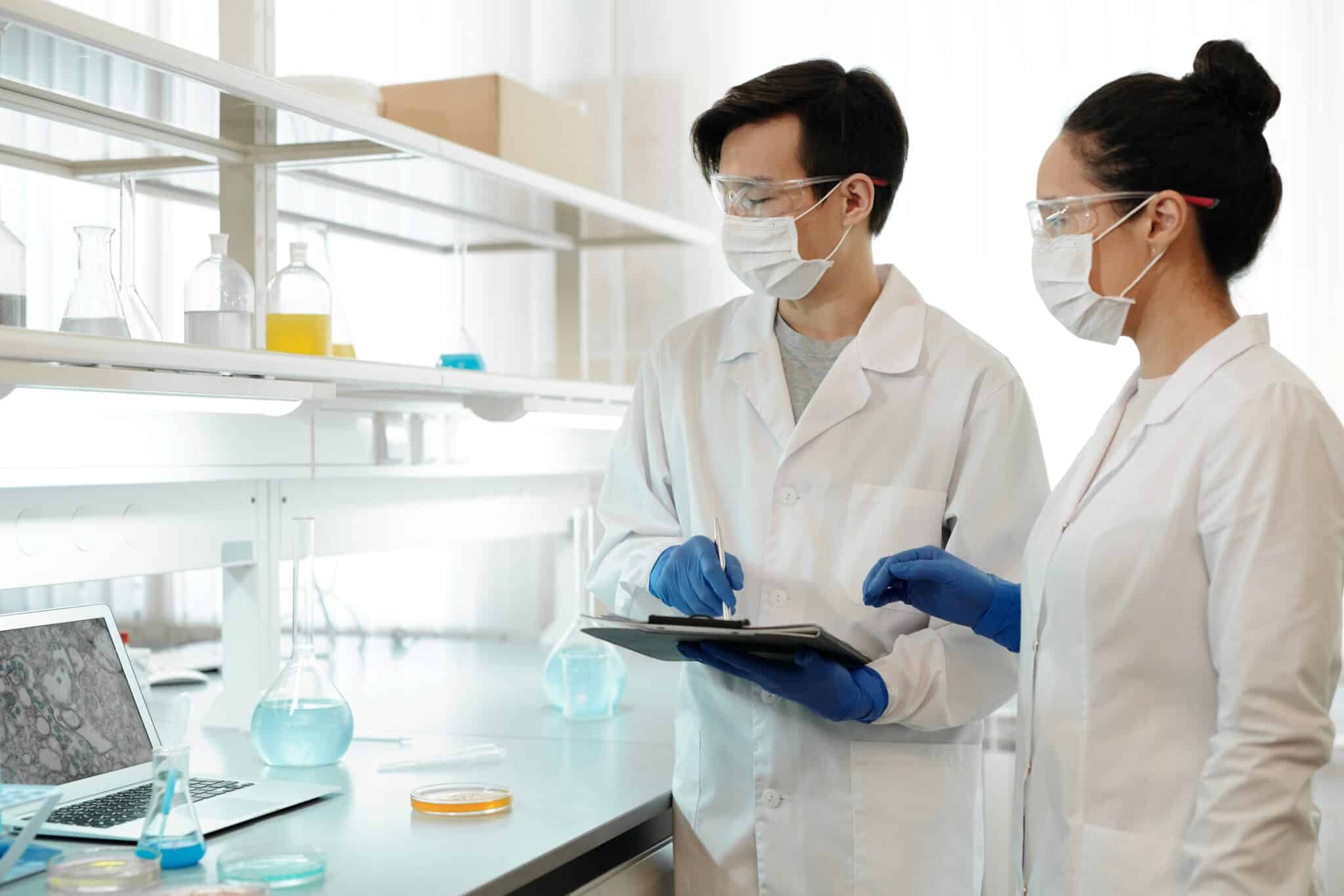 Two scientists working on a lab with protective gear.