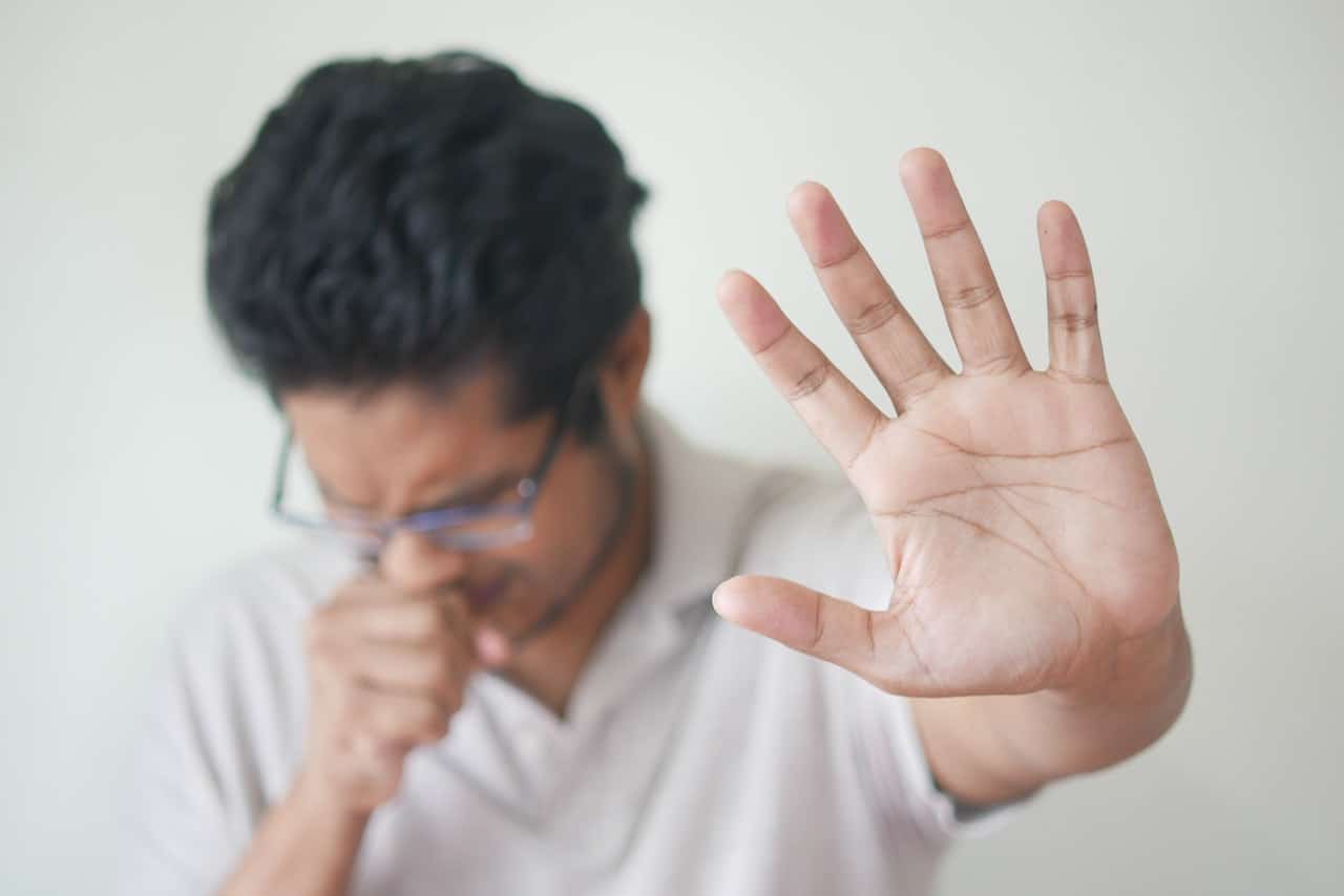 Young man coughing, showing sings of bird flu symptoms.