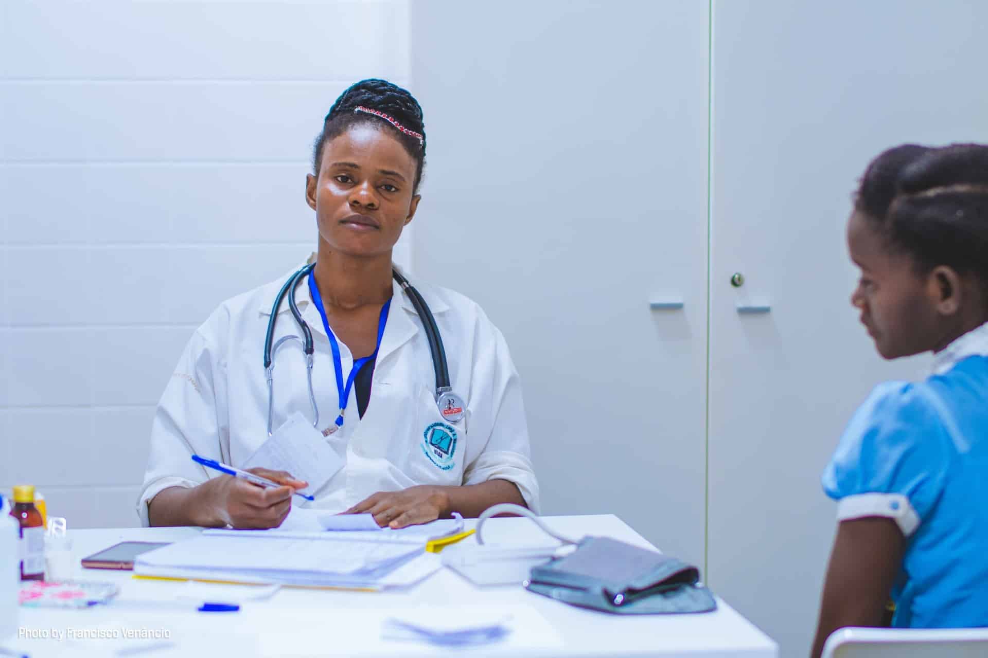 Female doctor evaluating child patient experiencing symptoms of polio in Burundi.