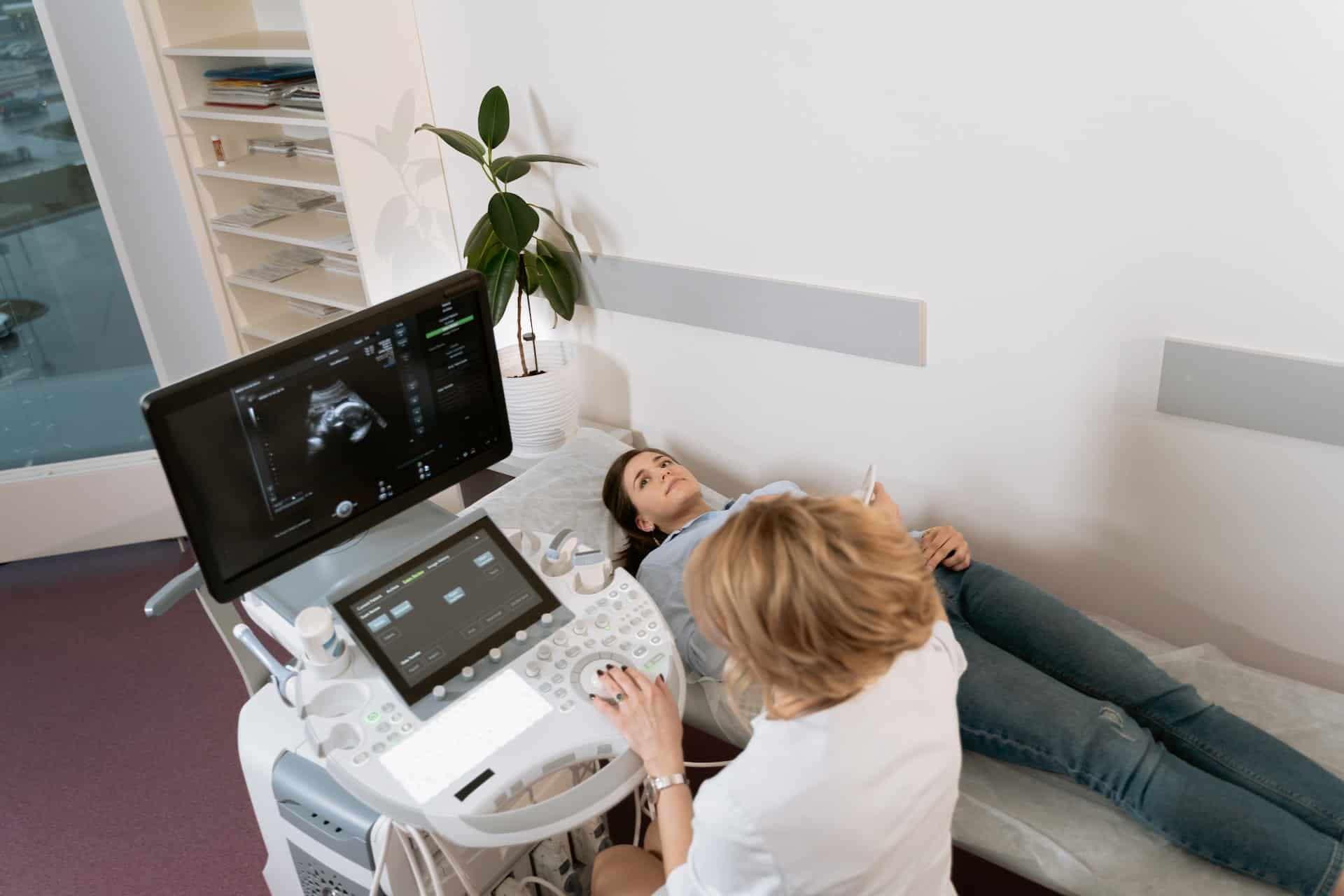 A female doctor performing an ultrasound on a pregnant woman in her fertility clinic.